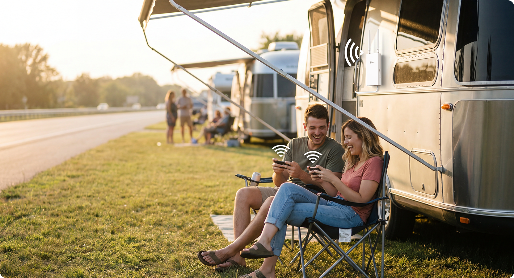 Two people using devices connected to a router outside of a motorhome