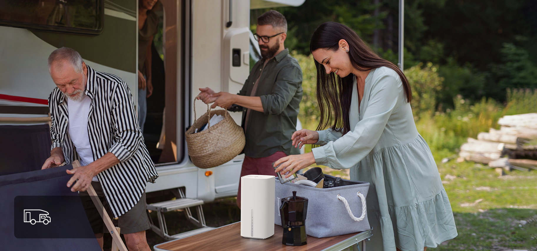 Two people using devices connected to a router outside of a motorhome