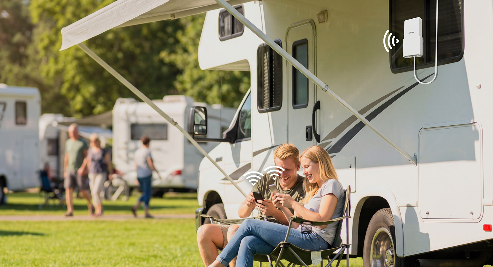 Zwei Personen, die Geräte benutzen, die mit einem Router außerhalb eines Wohnmobils verbunden sind.
