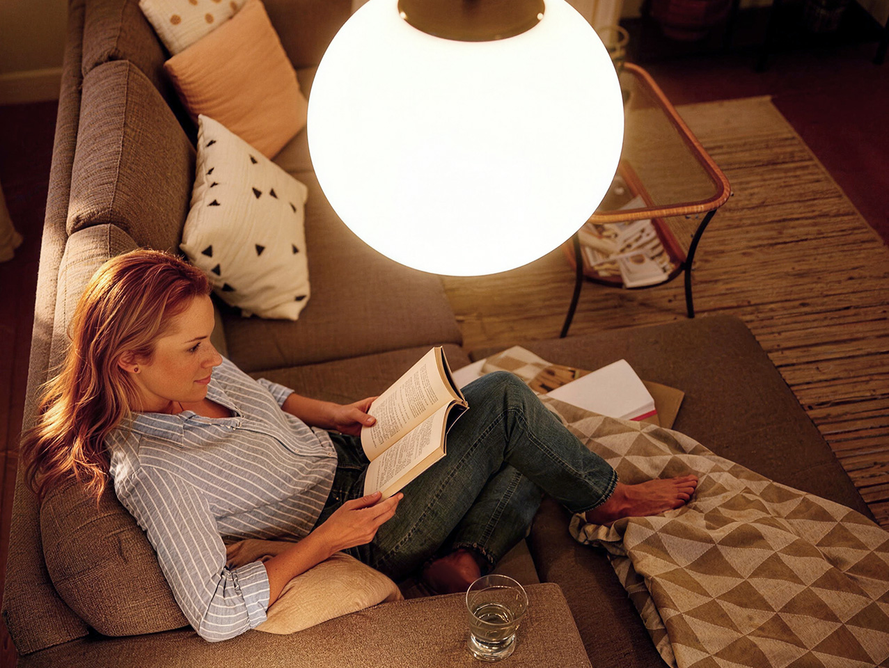 Woman reading under a lamp